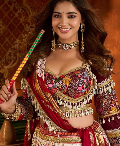 Maroon cowrie-shell chaniya choli with a dandiya stick